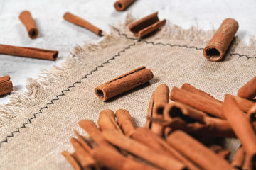Closeup detail - Cinnamon bark sticks scattered on beige linen tablecloth.