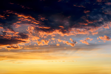 Dark thunderclouds with red orange reflections of the setting sun. Scenic storm clouds lit by the...