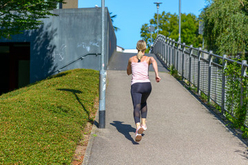 Fit woman jogging up a steep urban hill