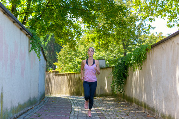 Fototapeta na wymiar Fit woman jogging down a leafy shady lane