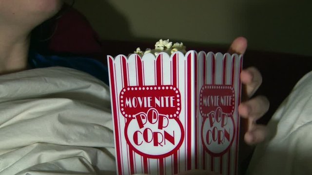 Movie nite popcorn cup being eaten by female watching tv