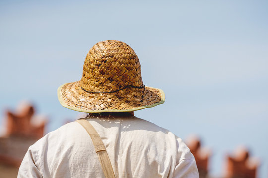 Man in white shirt and straw hat on blue sky background in sunny weather_
