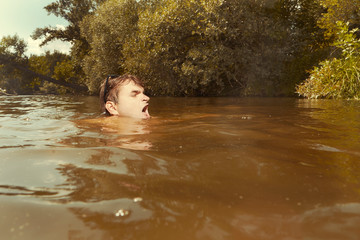 Funny man in sunglasses swimming in lake on inner tube