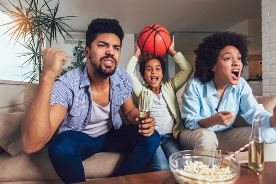 Família Afro-americana De Três Assistindo TV E Torcendo Jogos De Basquete  No Sofá Em Casa Foto de Stock - Imagem de feliz, basquete: 198337874