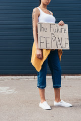 cropped view of feminist with word perfect on arm holding placard with inscription the future is...