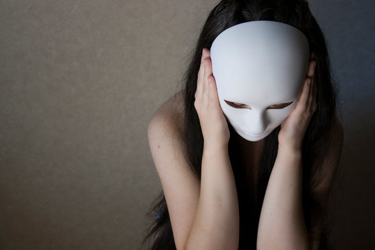 Masked young woman sitting in a dark room