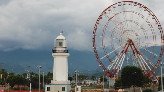timelapse Ferris wheel and Batumi lighthouse on the Batumi Seafront Promenade in the cloudy day, Adjara.