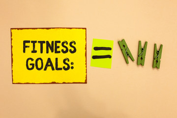 Word writing text Fitness Goals. Business concept for Loose fat Build muscle Getting stronger Conditioning Yellow piece paper reminder equal sign several clothespins sending message