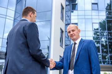 Fototapeta premium Friends in elegant business suits handshaking outdoors