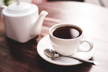 Teapot and cup of tea on wooden table.