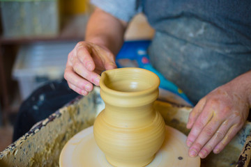 Professional male potter working with clay on potter's wheel