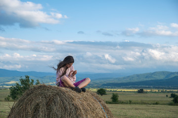 Naklejka na ściany i meble A girl sitting on a stack of hay
