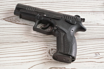 Simple modern black metal gun on white wooden boards table