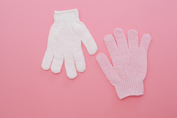 Woman exfoliating massage glove for shower on pink background.Gloves for use in the shower for massage and scrub. Beauty background with cosmetic products. Beauty, health and spa concept