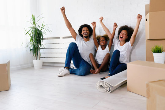 Young Happy African-american Family Unpacking after Move. Sitting on a Floor Resting at Their New Home.