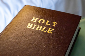 Holy Bible gold text on a leather cover book brown color, close up view.