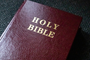 Holy Bible gold text on a leather cover book brown red color, close up view.