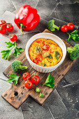 Vegetable frittata with broccoli, red bell pepper and red onion in cast iron skillet. View from above