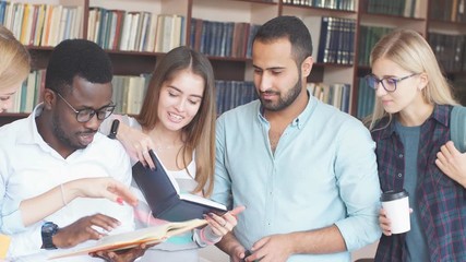Multiracial students having fun in library while preparing for exams.