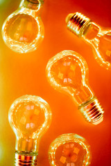 Creative pattern made of light bulbs in orange and red neon duotone. Flat lay. Macro.