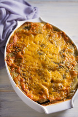 Traditional moussaka in baking dish on white wooden table