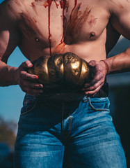 Halloween man with pumpkin in the street. Close-up portrait of a man with zombie makeup. The scary...