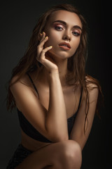 Fototapeta premium portrait of gorgeous sexy woman with perfect skin and long wet hair on dark background. girl looking at camera