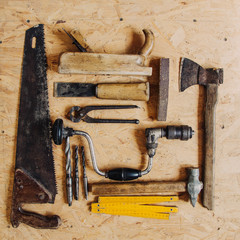 Old construction tools on a wooden workbench flat lay background. Carpenter table. Woodwork