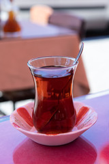 Turkish Cay Tea (çay is translated tee) at restaurant in Yenifoca in the Izmir province. Tea in clear traditional glass.