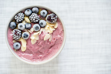 Healthy breakfast berry smoothie bowl topped with banana, granola, Blueberries and chia seeds with...