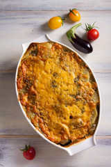 Traditional moussaka in baking dish on white wooden table. View from above, top studio shot