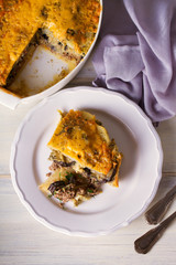Traditional moussaka on plate and in baking dish