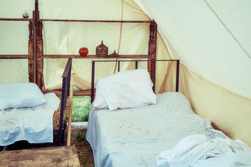Bed under a large tent retro field hospital. Military field medicine in the 18th or 19th century. Portable hospital for wounded soldiers.