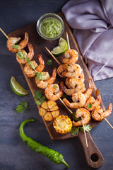 Skewered shrimps with garlic butter sauce served with cilantro and lime on serving board
