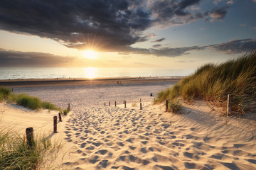 lumière dorée au coucher du soleil sur le chemin de sable vers la plage de la mer du Nord