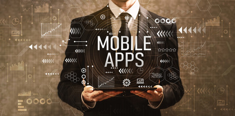 Mobile apps with businessman holding a tablet computer on a dark vintage background