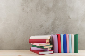 Education and reading concept - group of colorful books on the wooden table, concrete wall blackboard