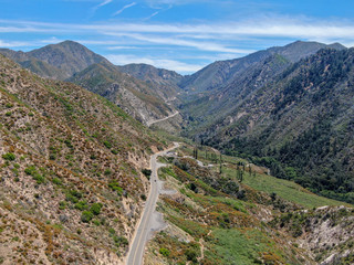 Asphalt road bends through Angeles National forests mountain, California, USA. Thin road winds between a ridge of hills and mountains at high altitude