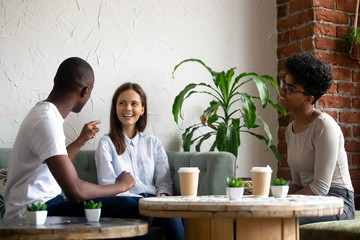 Smiling multiracial friends talk have fun in coffeeshop