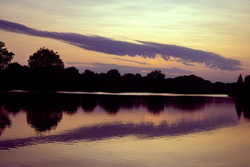 Summer sunset, woodland and reflections in the lake