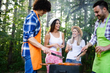 Happy friends camping and having a barbecue in nature