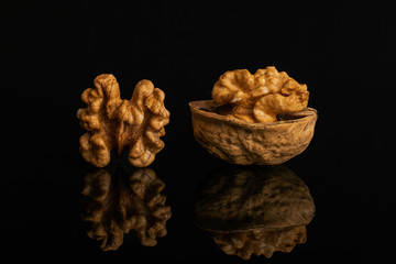 Group of two whole ripe brown walnut one is with half shell isolated on black glass
