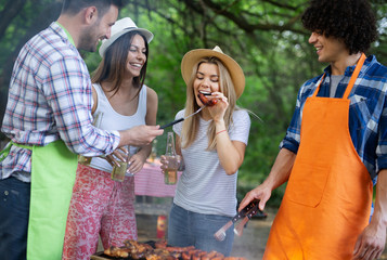 Happy friends camping and having a barbecue in nature