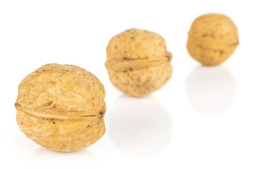 Group of three whole ripe brown walnut placed diagonally in line isolated on white background