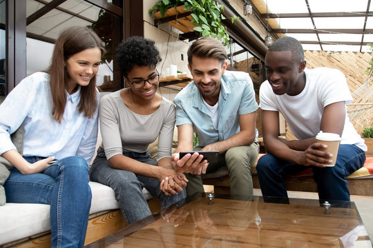 Smiling multiracial people relax watching video on cellphone