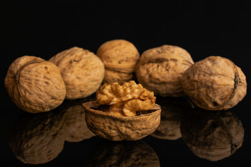 Group of six whole ripe brown walnut arranged symmetrically isolated on black glass