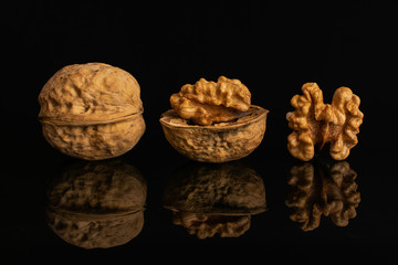 Group of three whole ripe brown walnut in row isolated on black glass