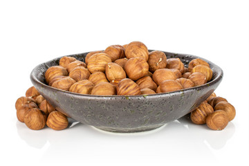 Lot of whole ripe brown hazelnut in dark ceramic bowl isolated on white background