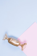 Decor in the shape of holidays candy with the gold glitter on a blue background. Pastel blue and pink backgeound.