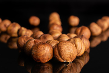 Lot of whole ripe brown hazelnut arranged symmetrically isolated on black glass